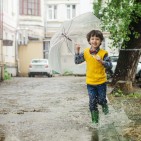 young boy running in rain with umbrella