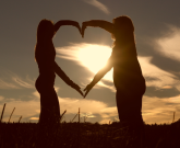 two friends making a heart with their arms